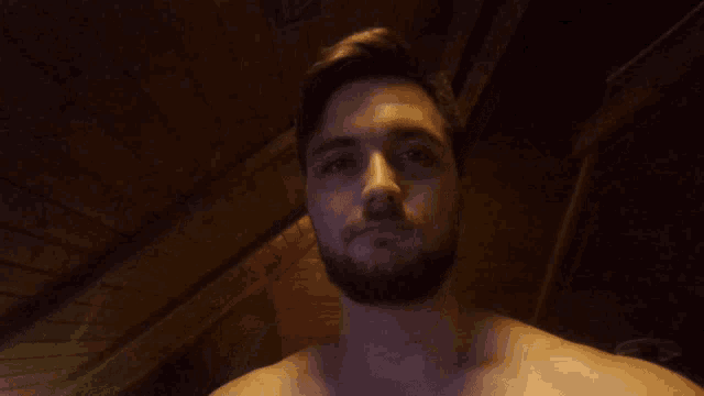 a shirtless man making a funny face with his hand up