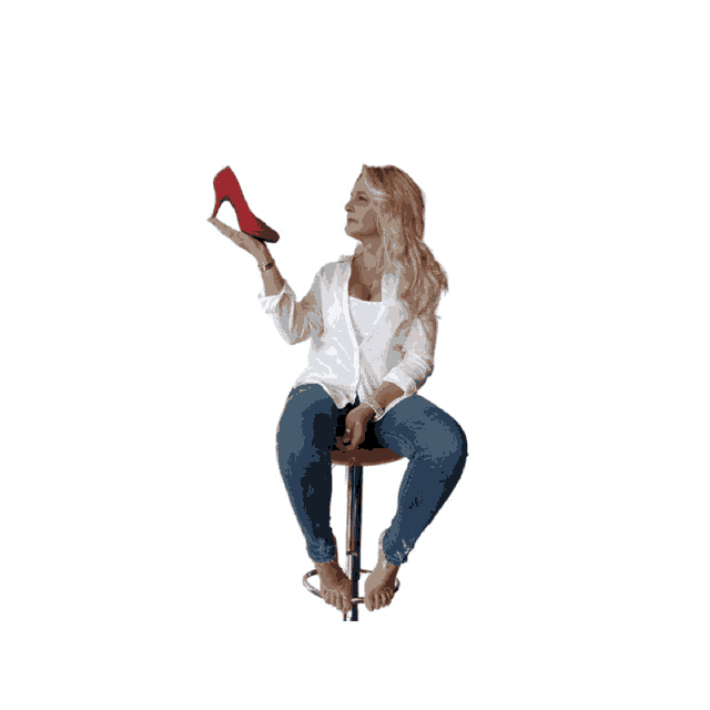 a woman sitting on a red stool holding a red high heel