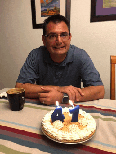 a man is sitting at a table with a pie and candles that say 41 on it
