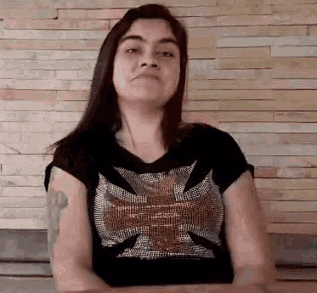 the woman is wearing a black shirt with a cross on it .