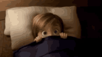 a cartoon character is peeking out from under a blanket .