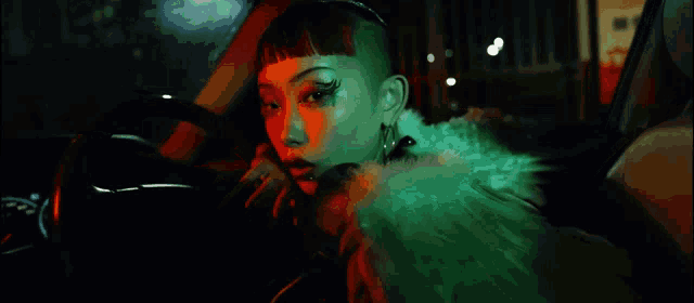 a woman in a green fur coat is sitting in a car at night
