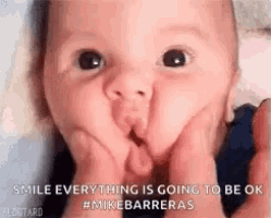 a baby is making a funny face while holding its hands to its face .