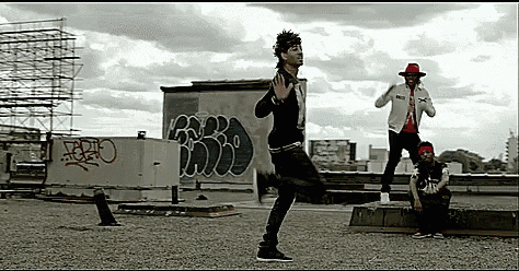 a group of people are dancing on a rooftop with graffiti on the wall behind them that says ario