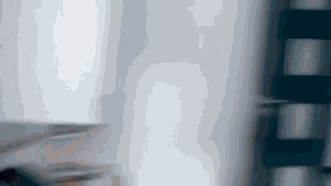 a blurry photo of a person standing in front of a white wall .