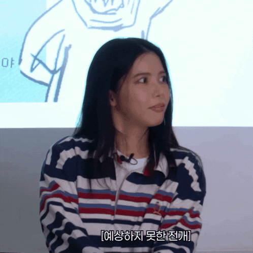 a woman wearing a striped sweater with a microphone on her neck is talking in a foreign language