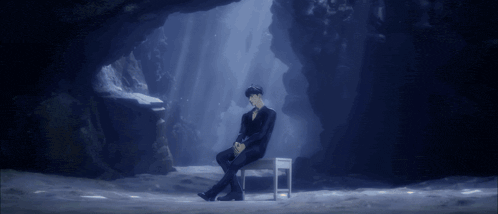 a man in a suit sits in a chair in a cave