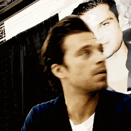 a close up of a man 's face with a picture of another man in the background