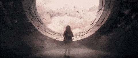 a woman is standing in front of a large window looking out at a flock of bats flying in the sky .