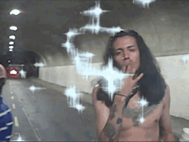 a shirtless man with long hair is standing in a tunnel smoking a cigarette