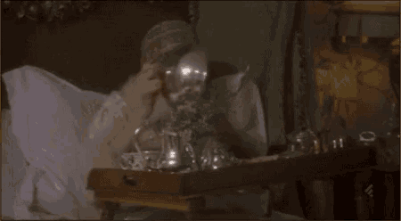 a woman is laying in bed with a tray of food on it