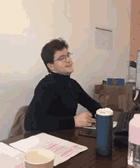 a man is sitting at a desk with a cup of coffee