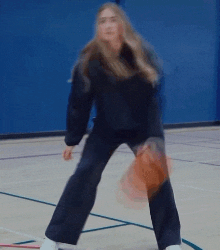 a blurry picture of a woman holding a basketball on a basketball court