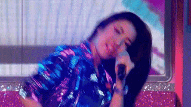 a woman in a sequined shirt is holding a microphone and dancing on a stage .