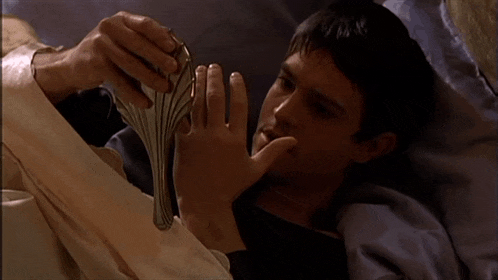a man is laying in bed holding a silver object