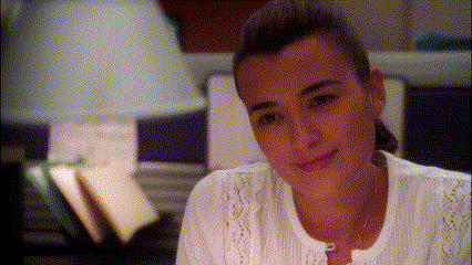 a woman in a white shirt looks at the camera with a lamp in the background
