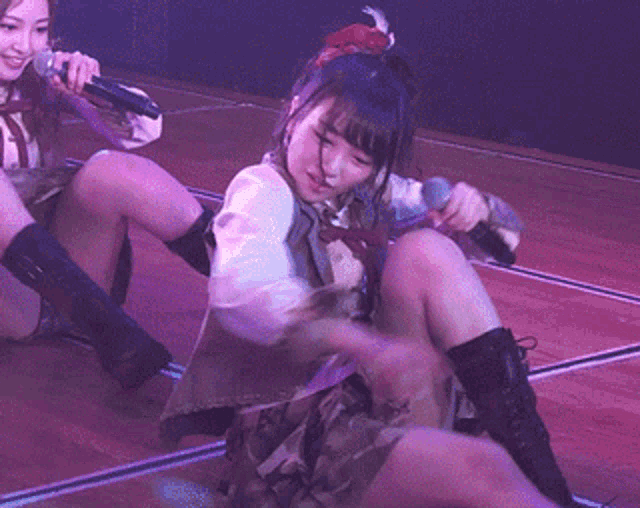 a woman holding a microphone while sitting on the floor