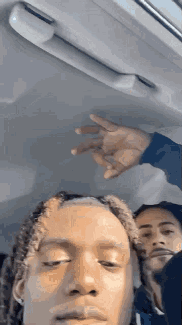 a man with dreadlocks is sitting in a car with another man .