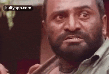 a man with a beard is making a funny face while wearing a green shirt .