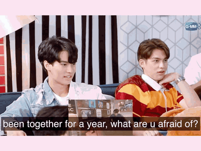 two young men are sitting on a couch and one of them says " been together for a year "