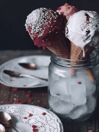 three ice cream cones in a jar with ice cubes on a table .