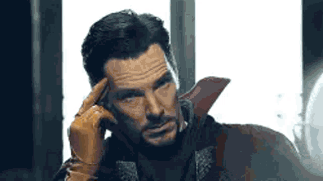 a man with a beard is holding his hand to his forehead and thinking .