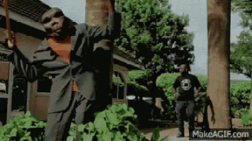 a man in a suit is standing in front of a tree holding a sword .