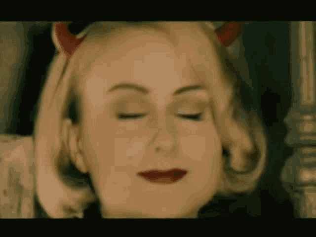 a close up of a woman wearing devil horns and red lips .