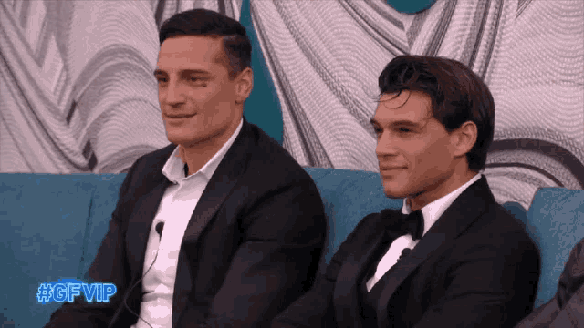 two men in tuxedos sit next to each other on a blue couch with the hashtag #gfvip on the bottom