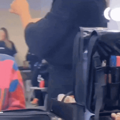a blurred image of a person standing in front of a mirror with a bag full of makeup behind them