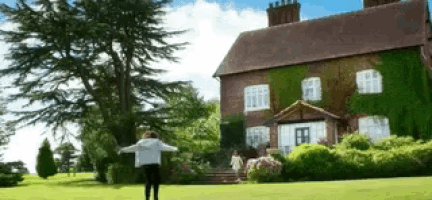 a woman is standing in front of a large brick house .
