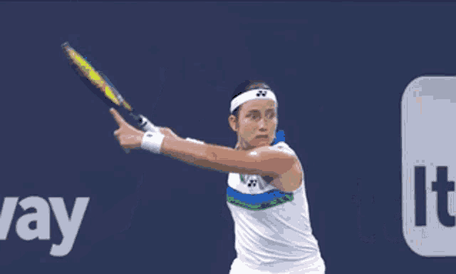 a woman is playing tennis in front of an itau sign