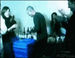 a group of people are gathered around a table with bottles of alcohol on it and a 4gifs.com watermark