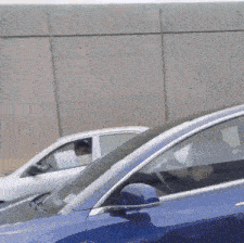 a blue car is parked next to a white car with a man sitting in the driver 's seat