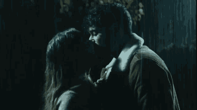 a man and woman are kissing in the rain at night