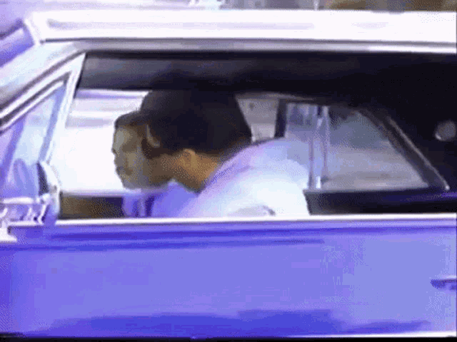 a man and woman are sitting in a blue car .