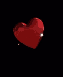 a red heart with a white star in the middle on a black background .
