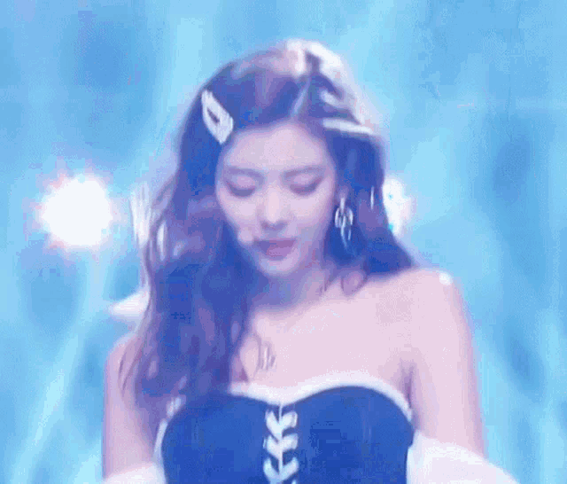 a woman is standing on a stage wearing a blue and white dress and earrings .