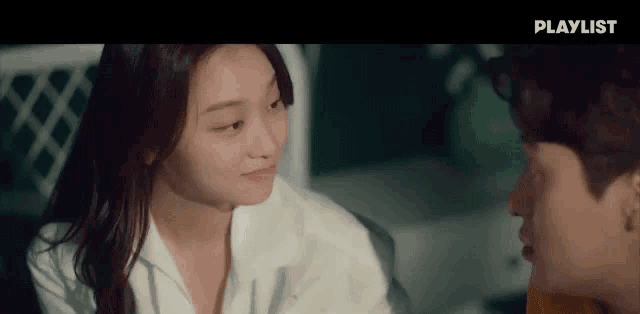 a man and a woman are looking at each other with a playlist advertisement in the background