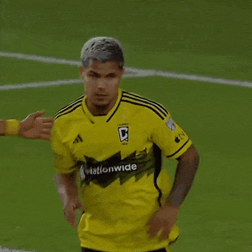 a soccer player wearing a yellow shirt that says nationwide on it