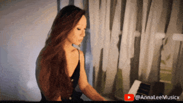 a woman is playing a piano with a youtube logo behind her