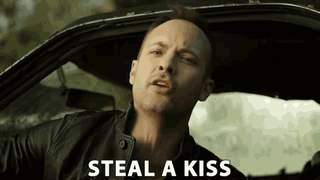 a man in a car with the words " steal a kiss " above him