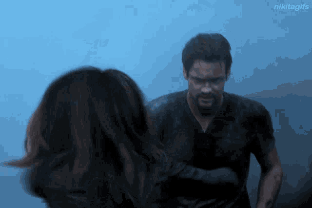 a man and a woman are standing next to each other in a foggy room with nikitagifs in the corner
