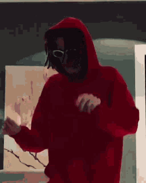 a person wearing a red hoodie and sunglasses is dancing in a room .