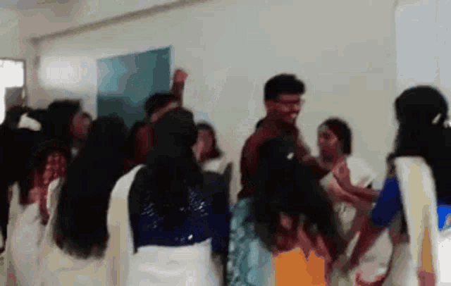 a group of people are dancing in a room with their hands in the air