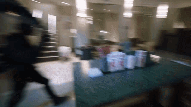 a blurry picture of a person walking in a room with a few boxes on a table