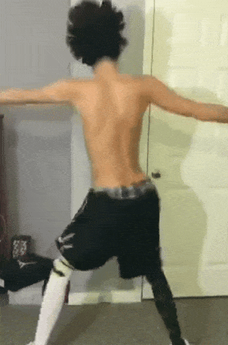 a shirtless man is dancing in front of a door