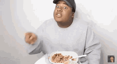 a man is sitting at a table eating a bowl of food with a fork .