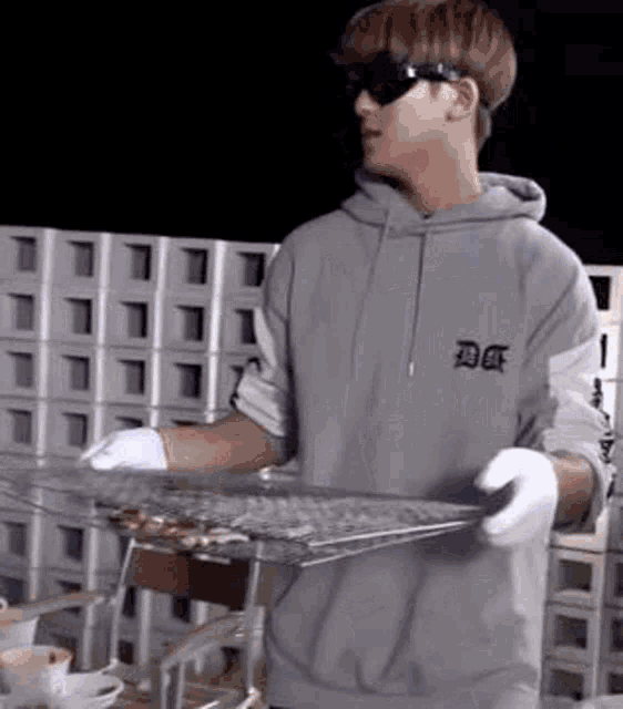 a man wearing sunglasses is holding a tray of food .