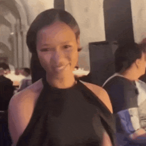 a woman in a black dress is smiling and looking at the camera .